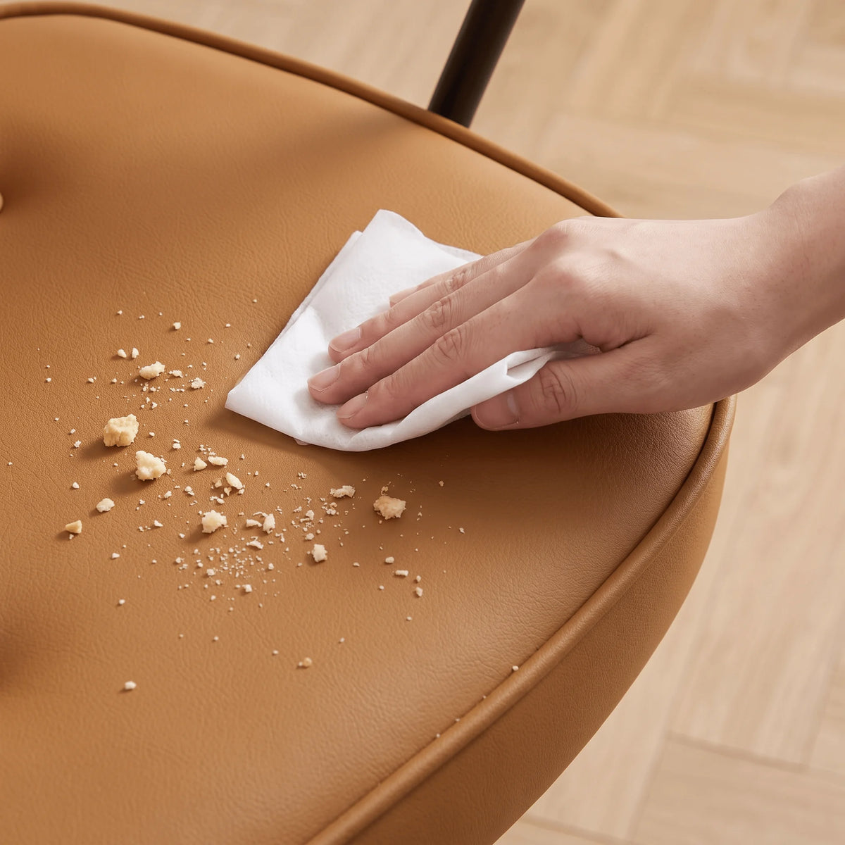 Burnt orange chair seat wiped with cloth, showing dust and crumbs