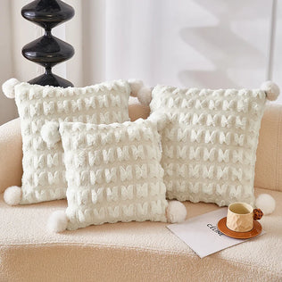 Cream plush throw pillow with waffle texture and pom-pom trim