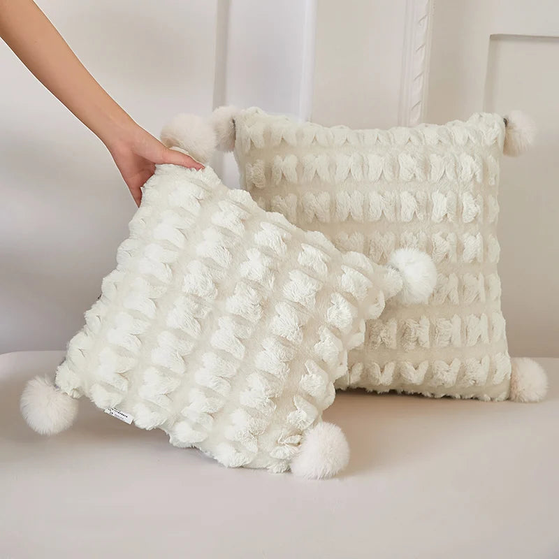 Cream plush throw blanket with waffle texture and pom-pom fringe along the edge